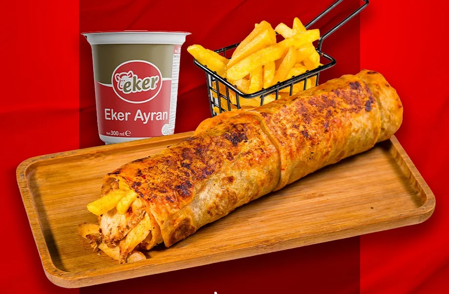 Chicken dürüm with sauce on a wooden board, with fries and ayran